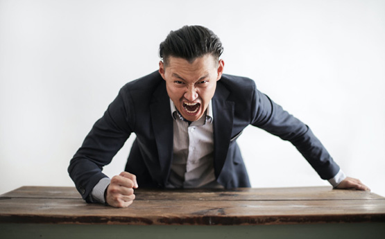 A man angrily slamming his fist on a table