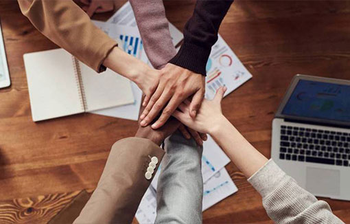 A group of students all putting their hands together in the middle