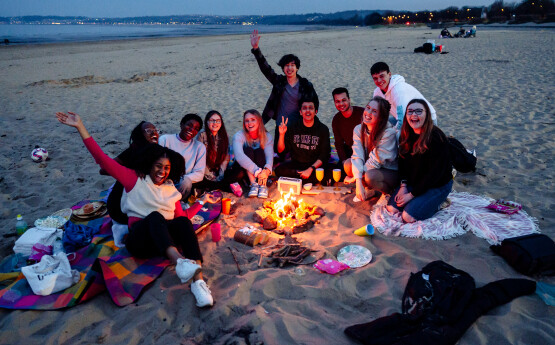 Students on the beach around a fire