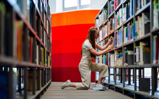 student looking at bookshelf in library