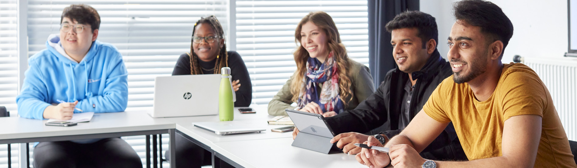 a group of people sitting around a rectangle desk smilling