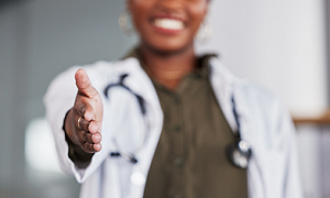 medical professional extending their hand to the camera in greeting