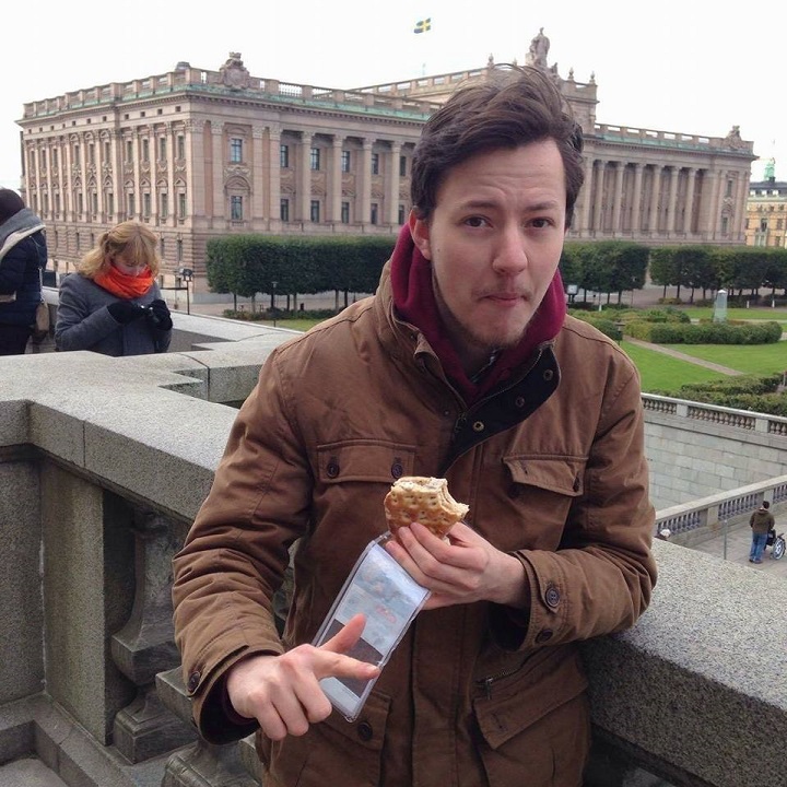Male student eating outside building in Stockholm