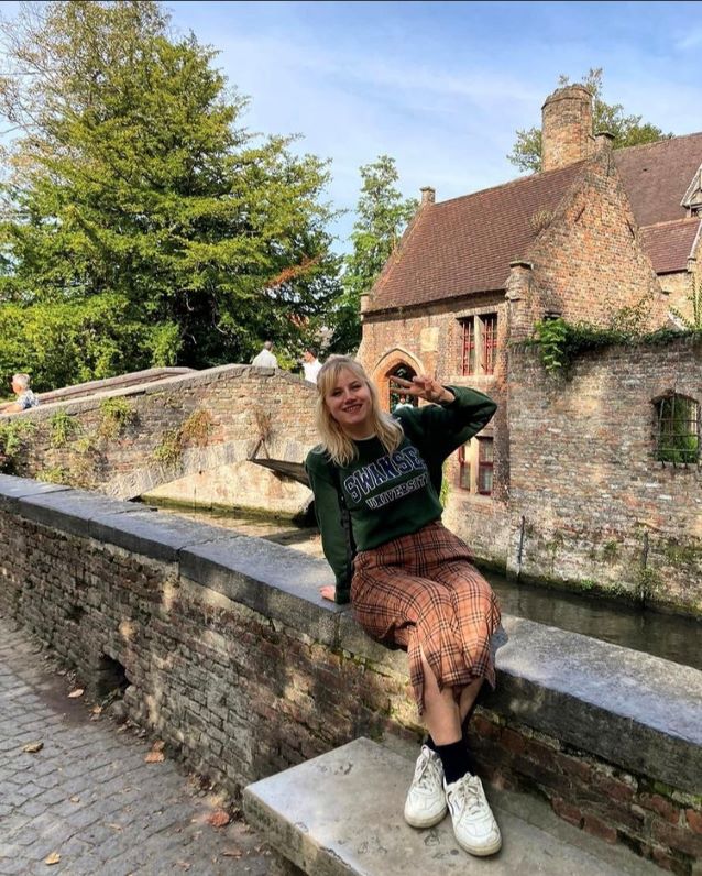 Student sitting on a wall, making peace sign