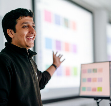 Lecturer standing in front of a large screen presenting