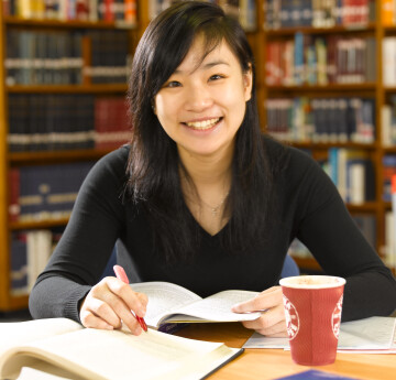 A student reading books at a library desk