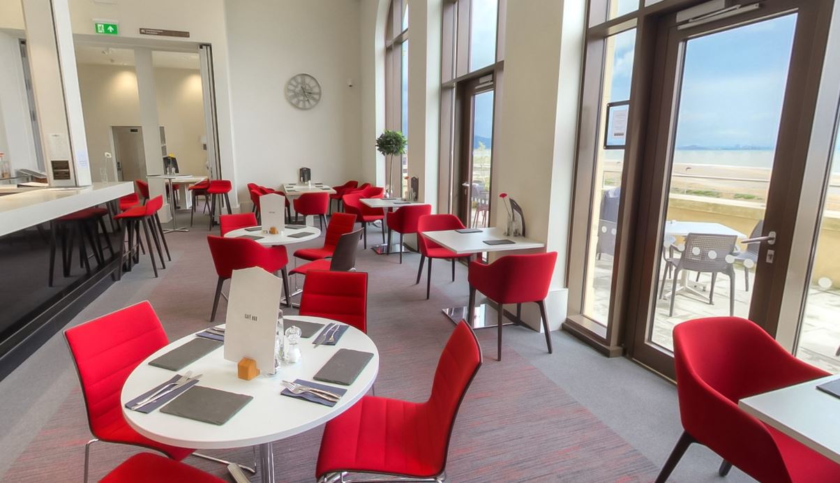 bar area with red seats, menu on table and windows with ocean view