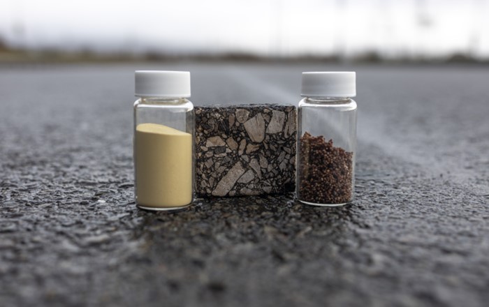 Two small bottles with powders flank a block of asphalt on a road.