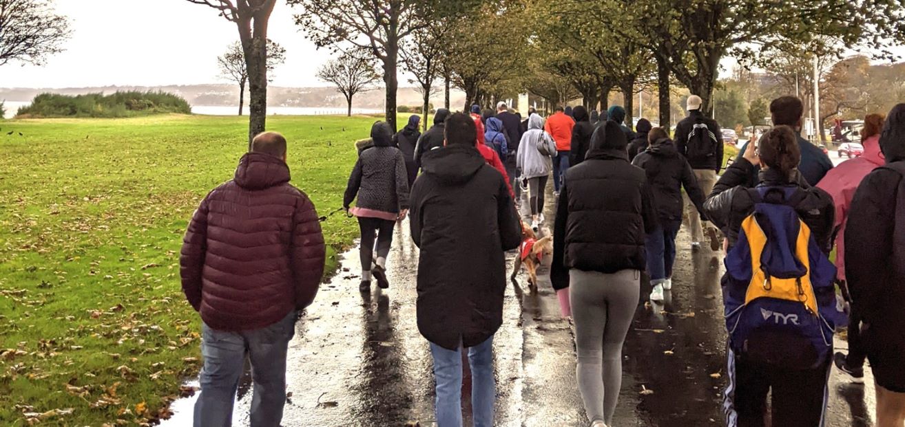 Group of people walking along a footpath near the sea