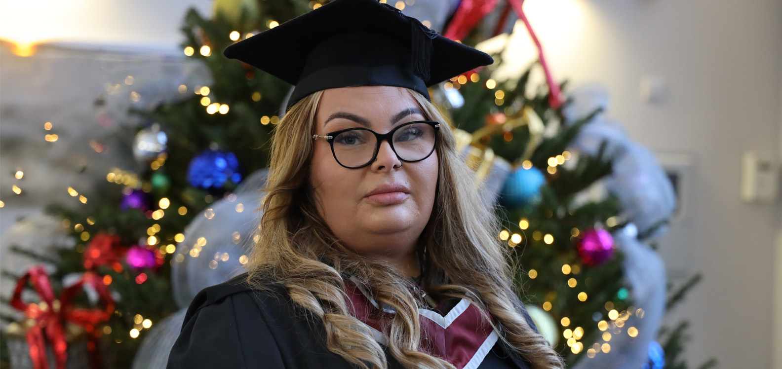 A photo of Holly Williams wearing a cap and gown on the day of her graduation.