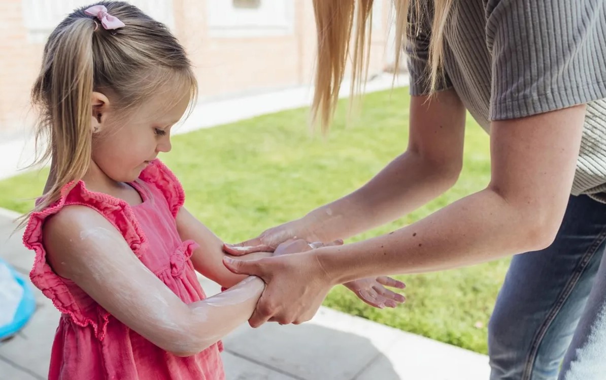 Adult applying sun cream to child