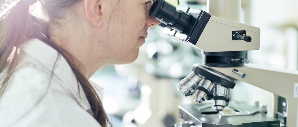 female medical student using a microscope