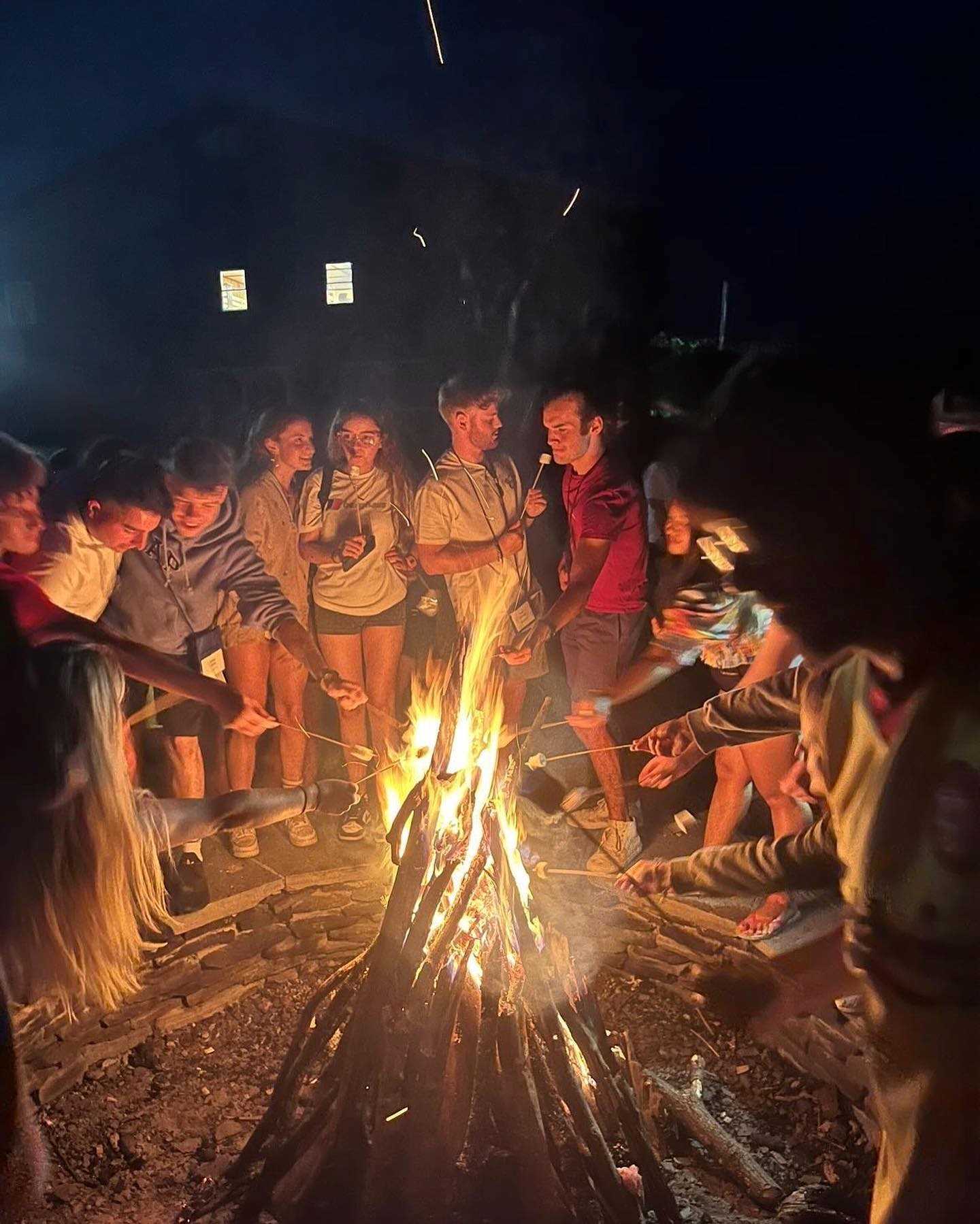 Group toasting marshmallows around a camp fire